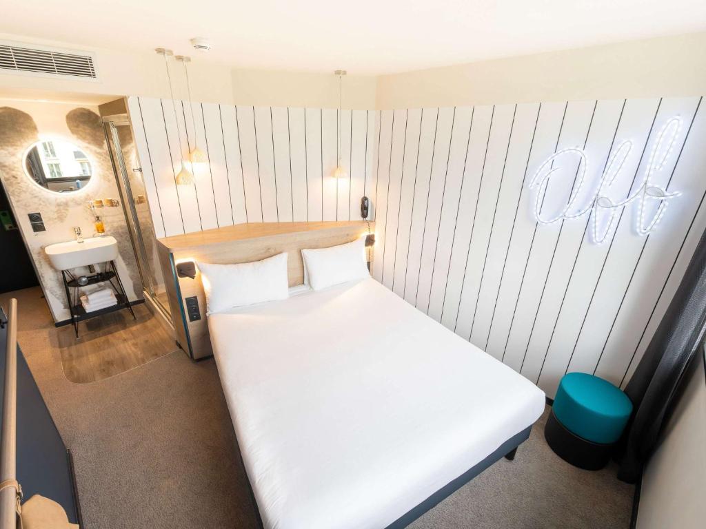 a bedroom with a white bed and a sign on the wall at ibis Styles Paris 16 Boulogne in Paris