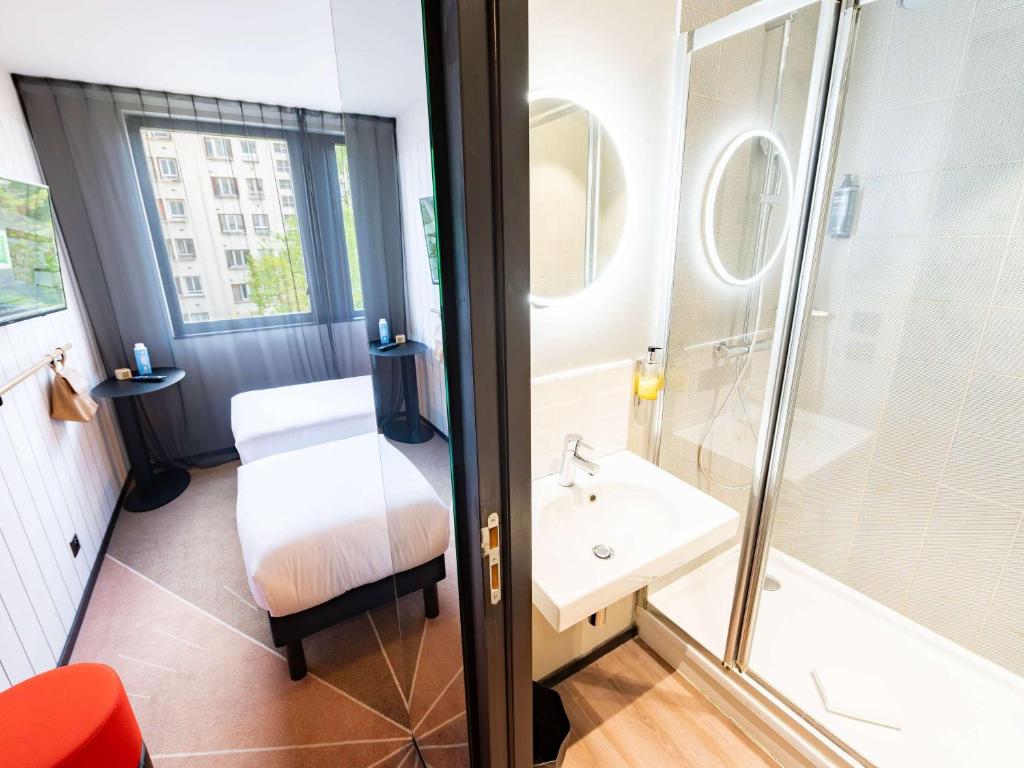 a bathroom with a bed and a shower and a sink at ibis Styles Paris 16 Boulogne in Paris