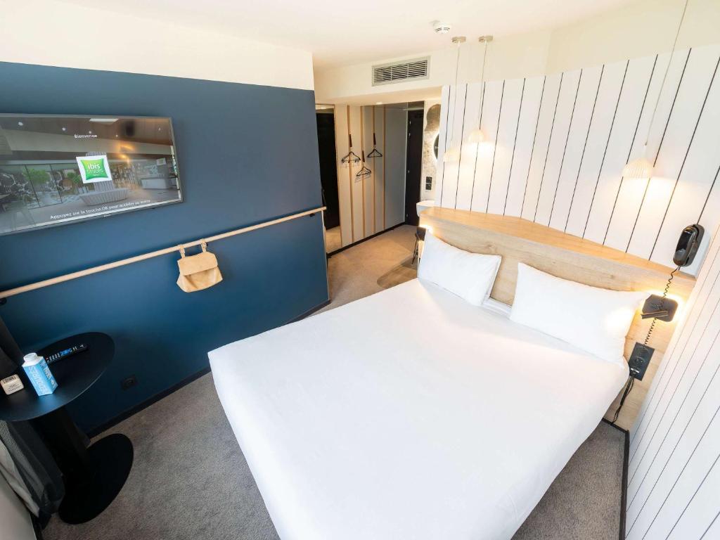 a bedroom with a white bed and a blue wall at ibis Styles Paris 16 Boulogne in Paris