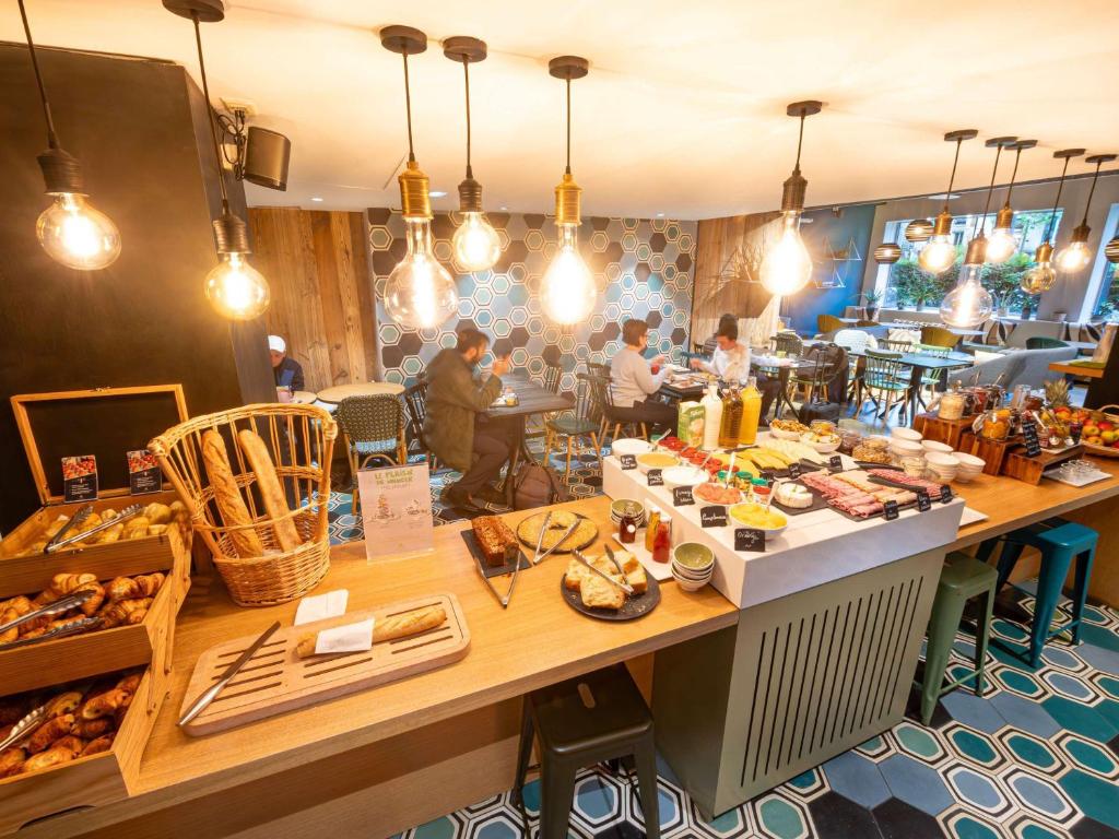 a restaurant with a long table filled with food at ibis Styles Paris 16 Boulogne in Paris