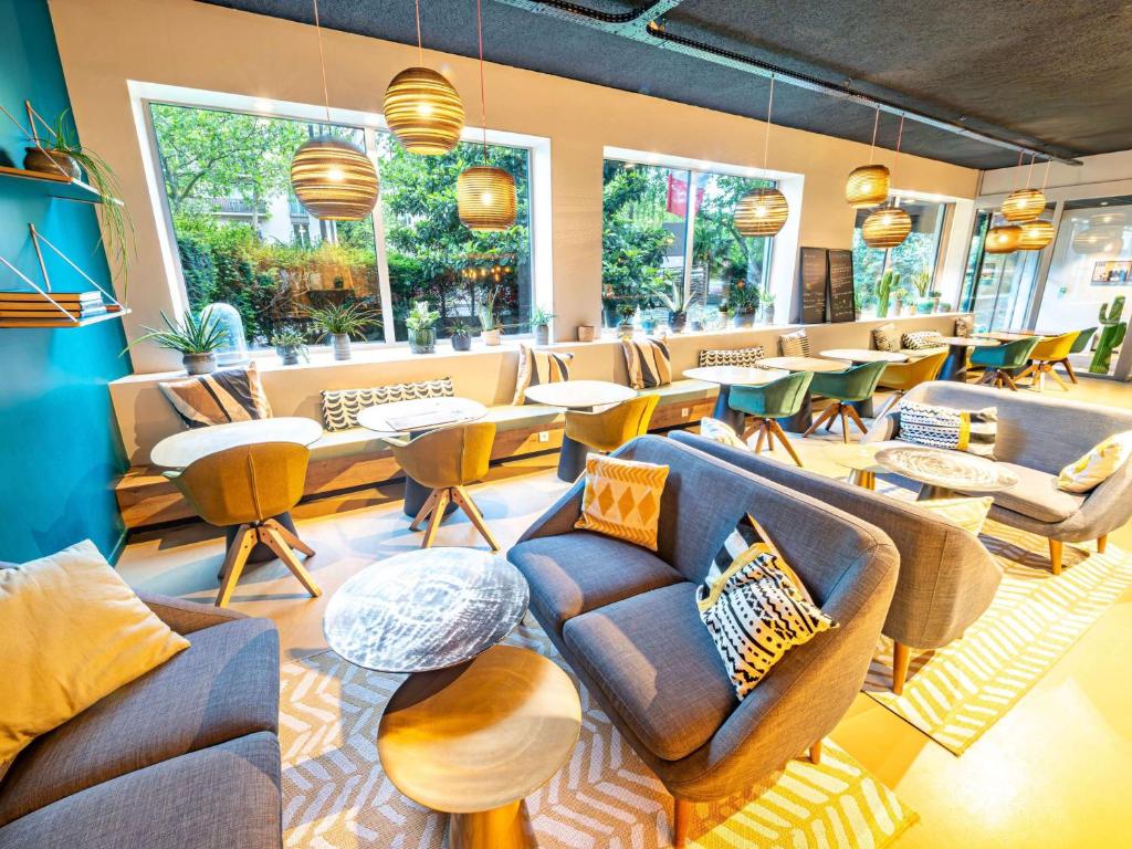 a waiting room with couches and tables and windows at ibis Styles Paris 16 Boulogne in Paris
