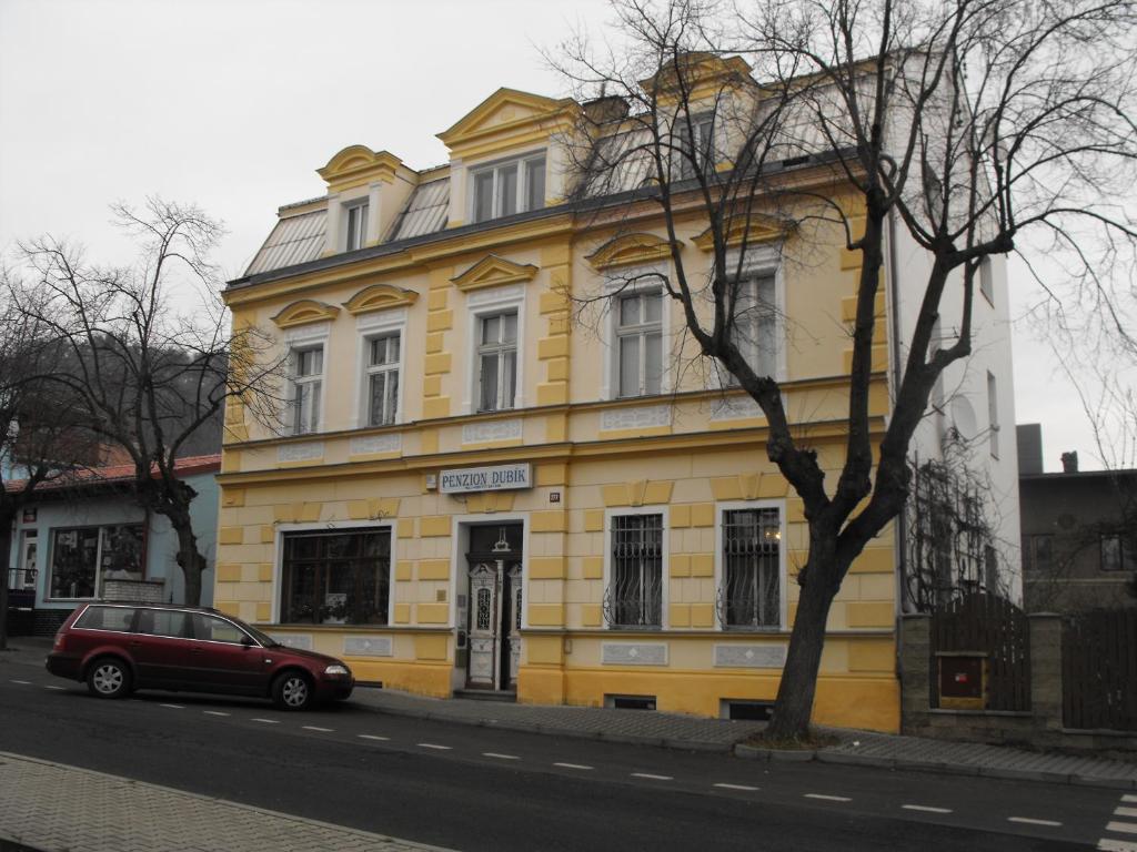 un'auto rossa parcheggiata di fronte a un edificio giallo di Penzion Dubík a Dubí