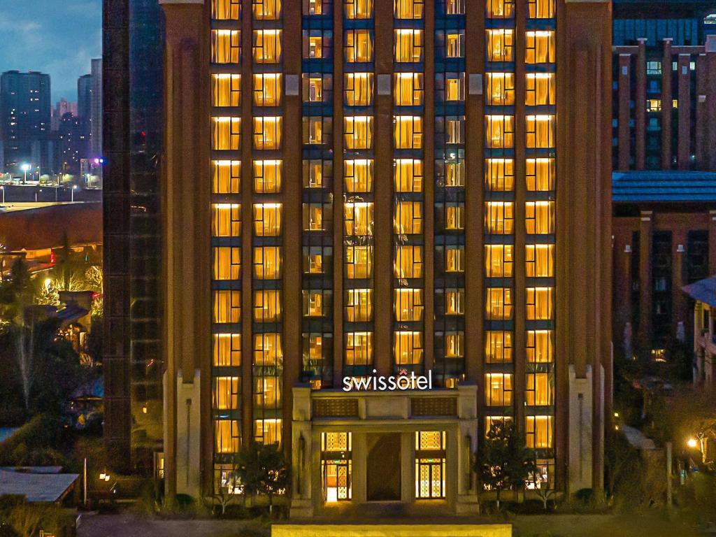 een hoog gebouw met een Swissotel-bord erop bij Swissotel Xi' an Xinxing Hot Spring in Xi'an