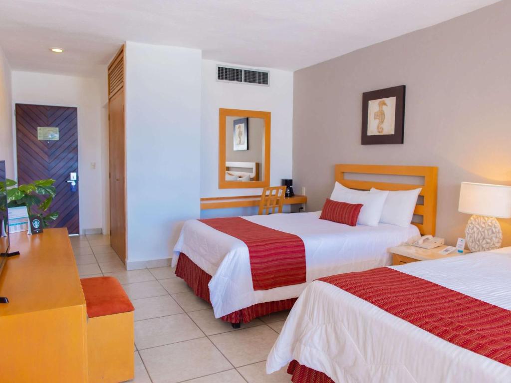 a hotel room with two beds and a desk at Marival Emotions Resort & Suites Riviera Nayarit by Mercure in Nuevo Vallarta
