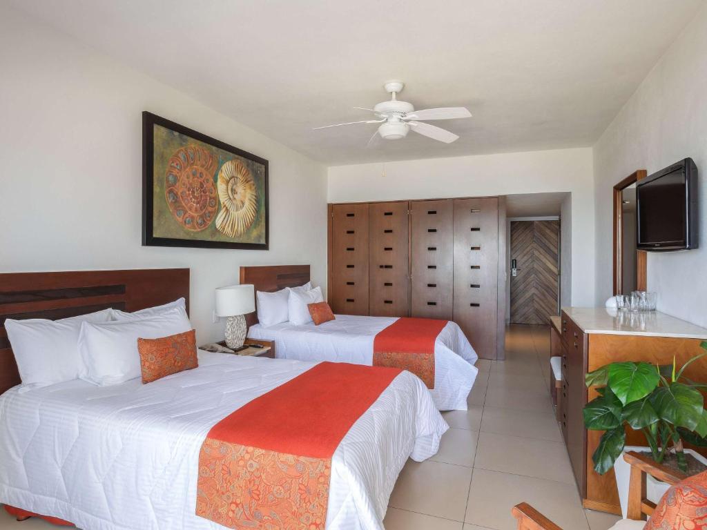 a hotel room with two beds and a television at Marival Emotions Resort & Suites Riviera Nayarit by Mercure in Nuevo Vallarta