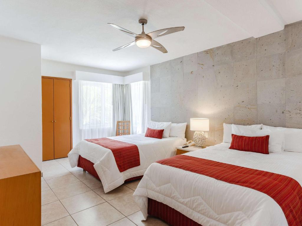 a bedroom with two beds and a ceiling fan at Marival Emotions Resort & Suites Riviera Nayarit by Mercure in Nuevo Vallarta