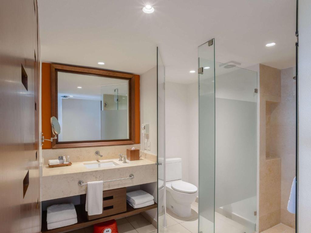 a bathroom with a sink and a glass shower at Marival Emotions Resort & Suites Riviera Nayarit by Mercure in Nuevo Vallarta