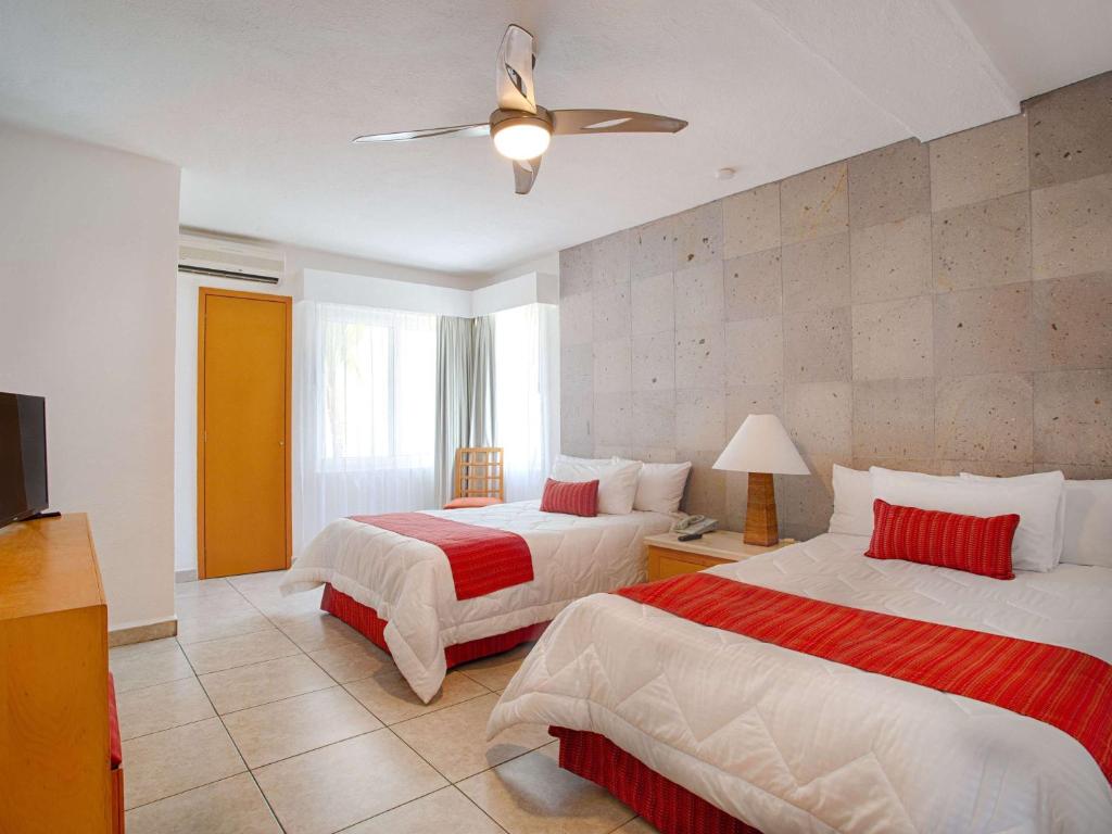 a bedroom with two beds and a ceiling fan at Marival Emotions Resort & Suites Riviera Nayarit by Mercure in Nuevo Vallarta