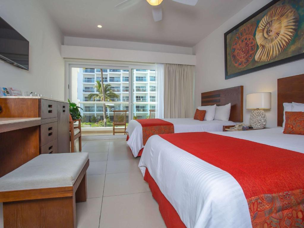 a hotel room with two beds and a window at Marival Emotions Resort & Suites Riviera Nayarit by Mercure in Nuevo Vallarta