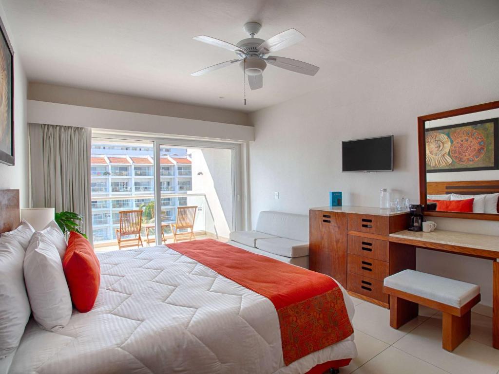 a bedroom with a large bed with a ceiling fan at Marival Emotions Resort & Suites Riviera Nayarit by Mercure in Nuevo Vallarta