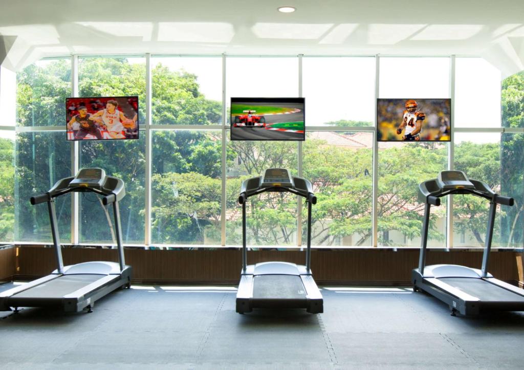 a gym with three treadmills in front of a large window at Wyndham Panbil Batam in Batam Center