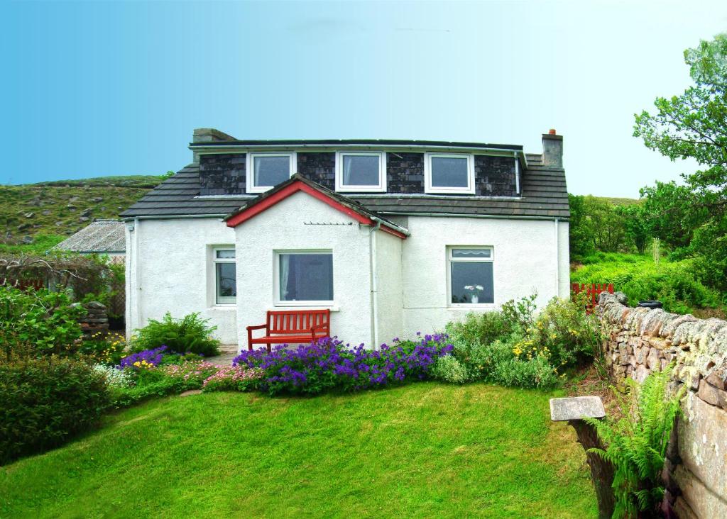 une maison blanche avec un banc dans une cour dans l'établissement Airdaniar Cottage, à Applecross