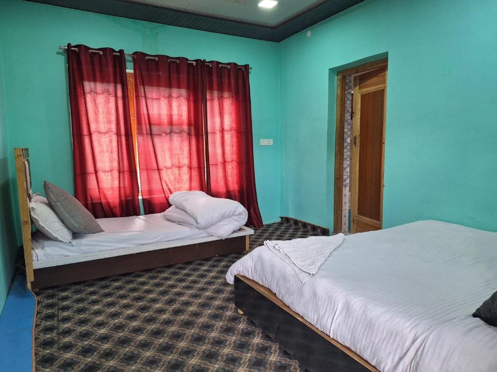 two beds in a room with blue walls and red curtains at Sangay Guest House Leh-Ladakh By LexStays in Leh