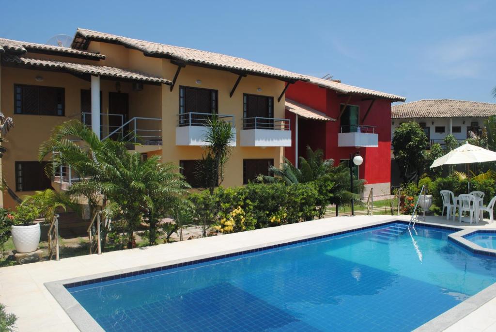a villa with a swimming pool in front of a building at Residence Vila Europa in Porto Seguro