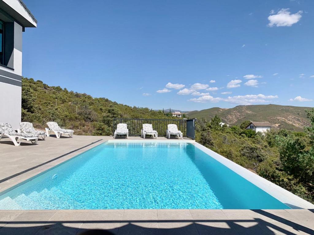 a swimming pool with chairs and a house at Chalet a estrenar, espectaculares vistas a la montaña in Torremocha de Jarama