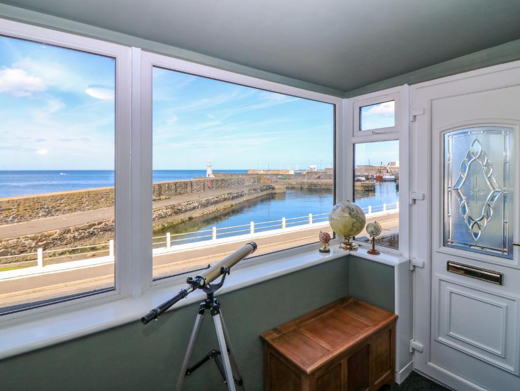 a camera in a room with a view of the ocean at West Pier Cottage in Macduff