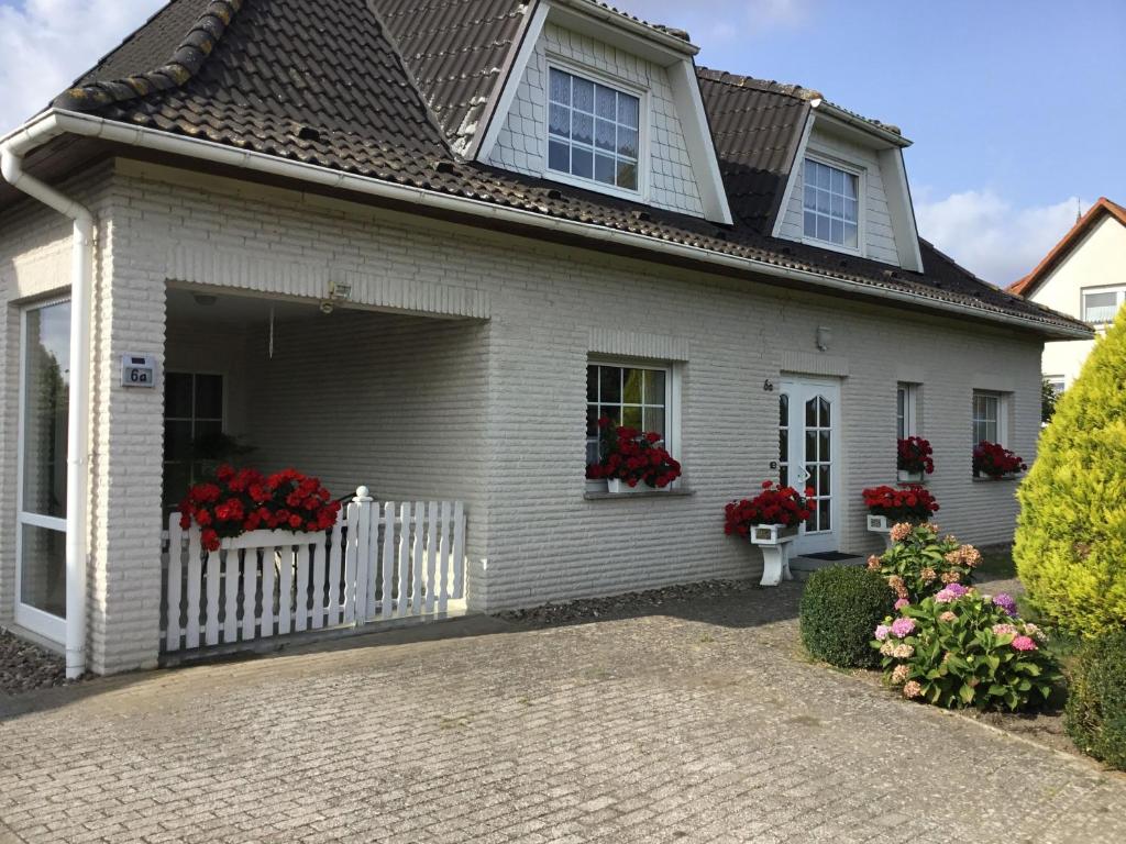 a white house with red geraniums in the window at Ferienwohnung an der Müritz 1 Groß in Bollewick