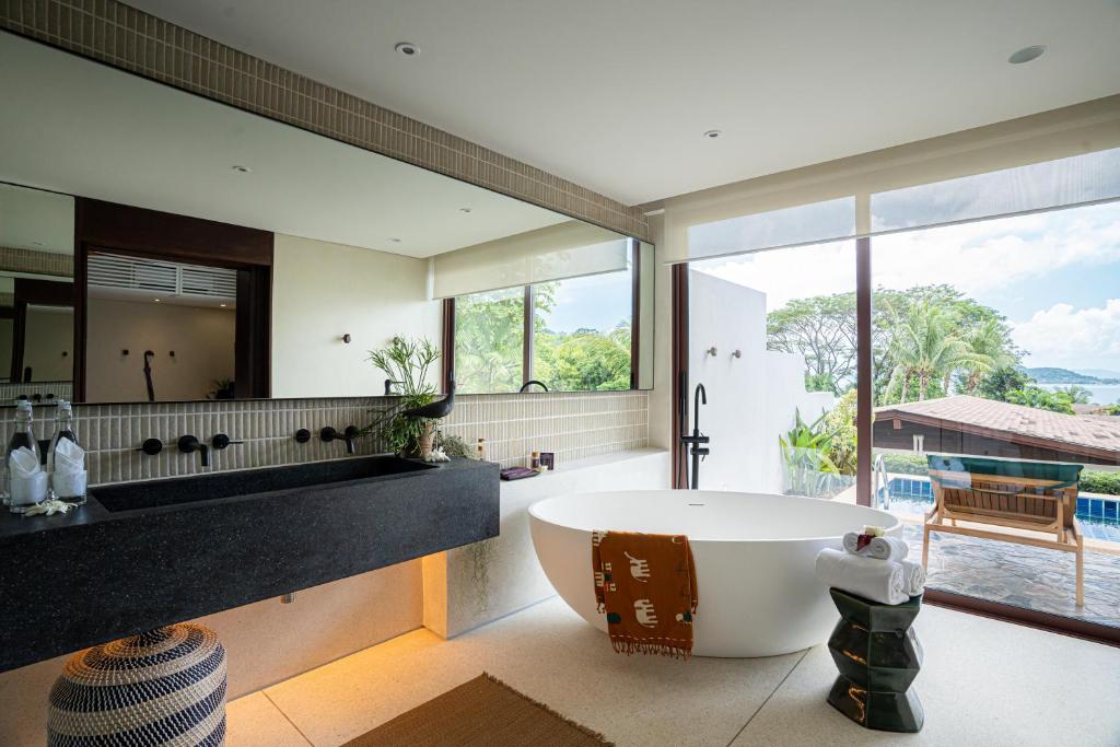 a bathroom with a large tub and a large window at Barcelo Coconut Island, Phuket in Phuket Town