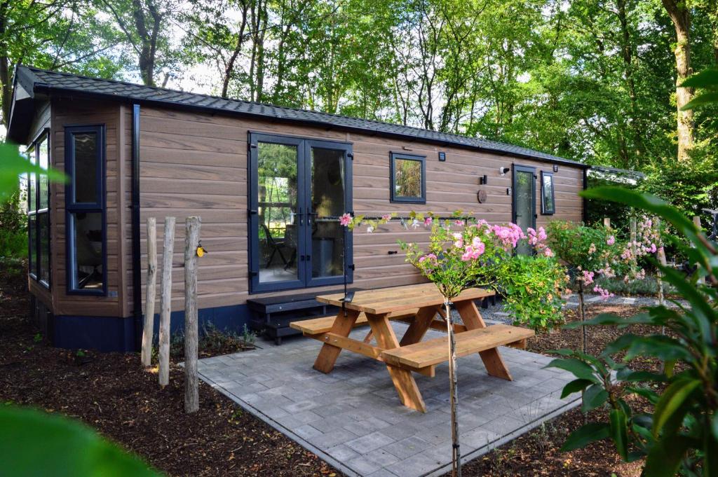 a wooden cabin with a picnic table and flowers at Gezellig vakantiechalet in bosrijke omgeving op de Veluwe in Epe