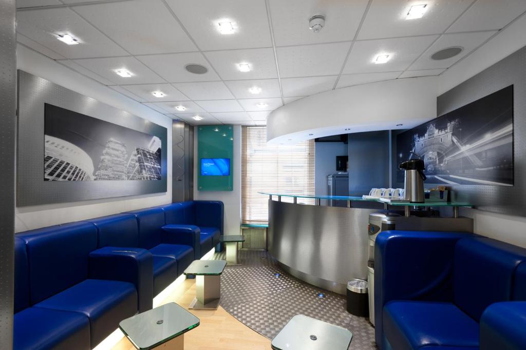 a waiting room with blue chairs and a bar at Stylotel in London