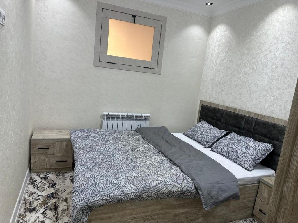 Un dormitorio con una cama y un cuadro en la pared. en Vokzal House, en Samarkand