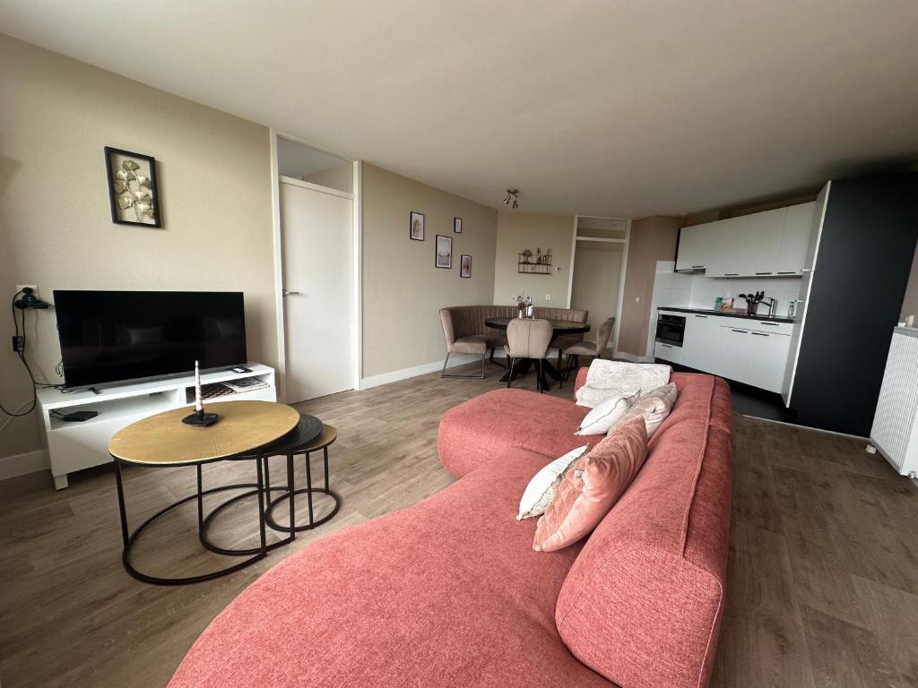 a living room with a red couch and a table at Appartement 'Zeeblick' in Burgerbrug