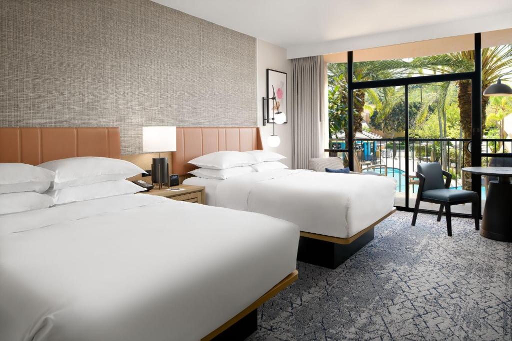 a hotel room with two beds and a balcony at Sheraton Park Hotel at the Anaheim Resort in Anaheim