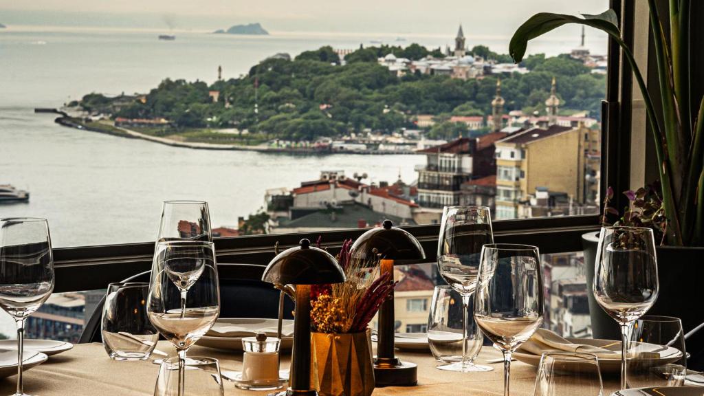 a table with wine glasses and a view of the water at CVK Park Bosphorus Hotel Istanbul in Istanbul