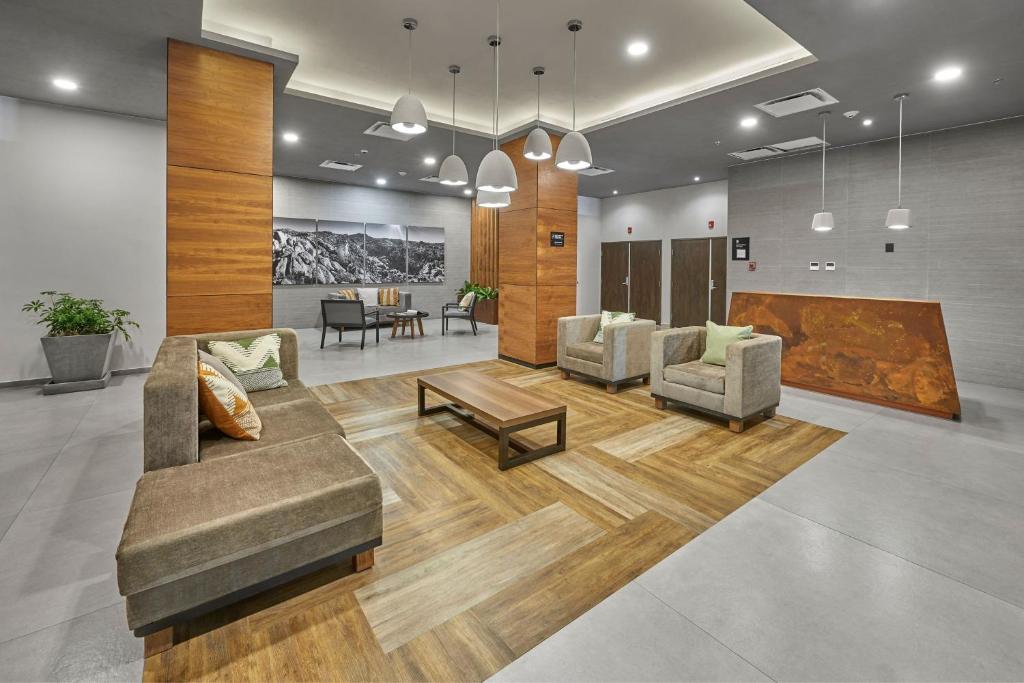 a lobby with two couches and a table and chairs at City Express Plus by Marriott Tijuana in Tijuana