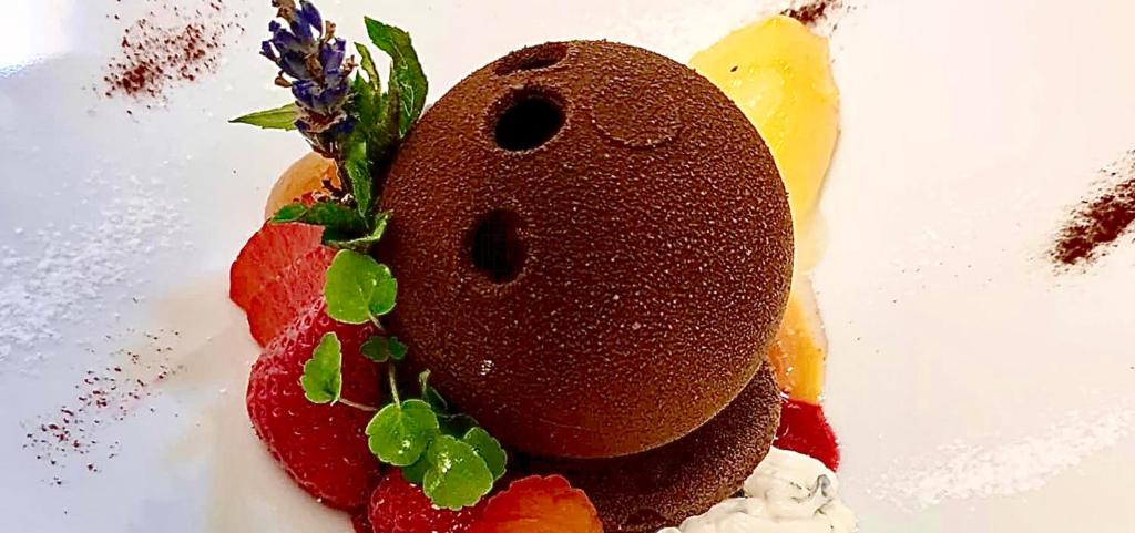 a chocolate dessert with fruit and flowers on top at Hotel Restaurant Le Cigalon in Waldbillig