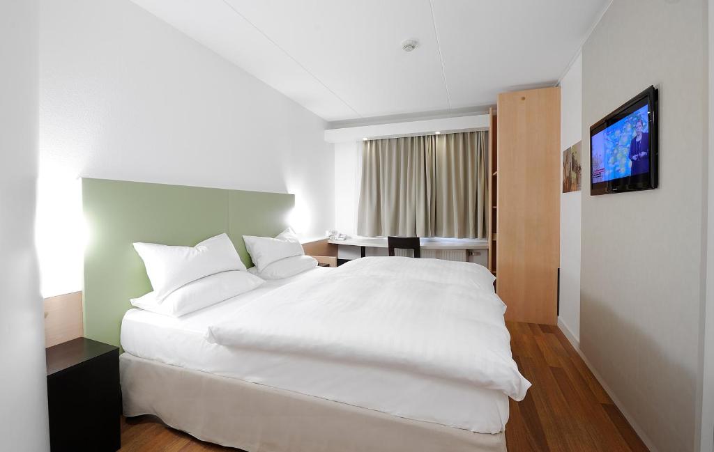 a bedroom with a white bed and a television at Good Morning Kista in Stockholm