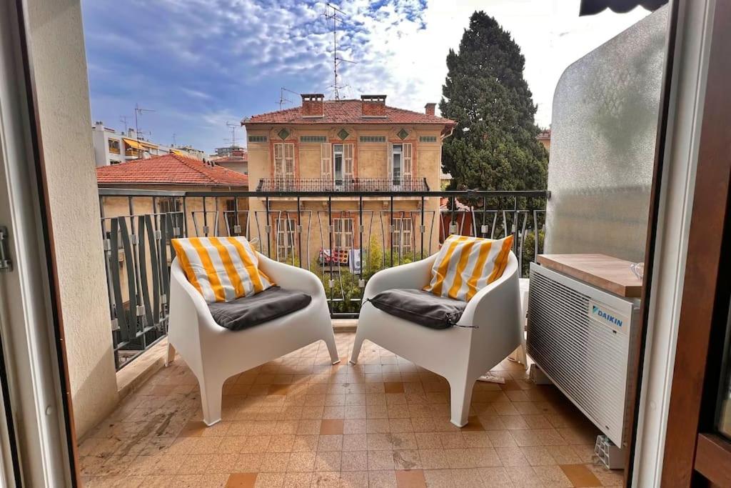 - un balcon avec deux chaises et un bâtiment dans l'établissement Le Villermont - Liberation Centre Ville, à Nice