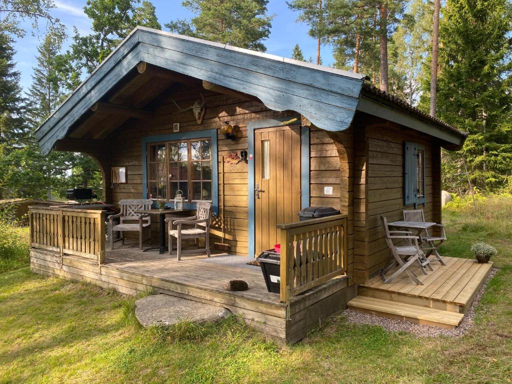 a cabin with a deck with a table at Timrad stuga i kanten av skogen med SPA möjlighet in Mullsjö