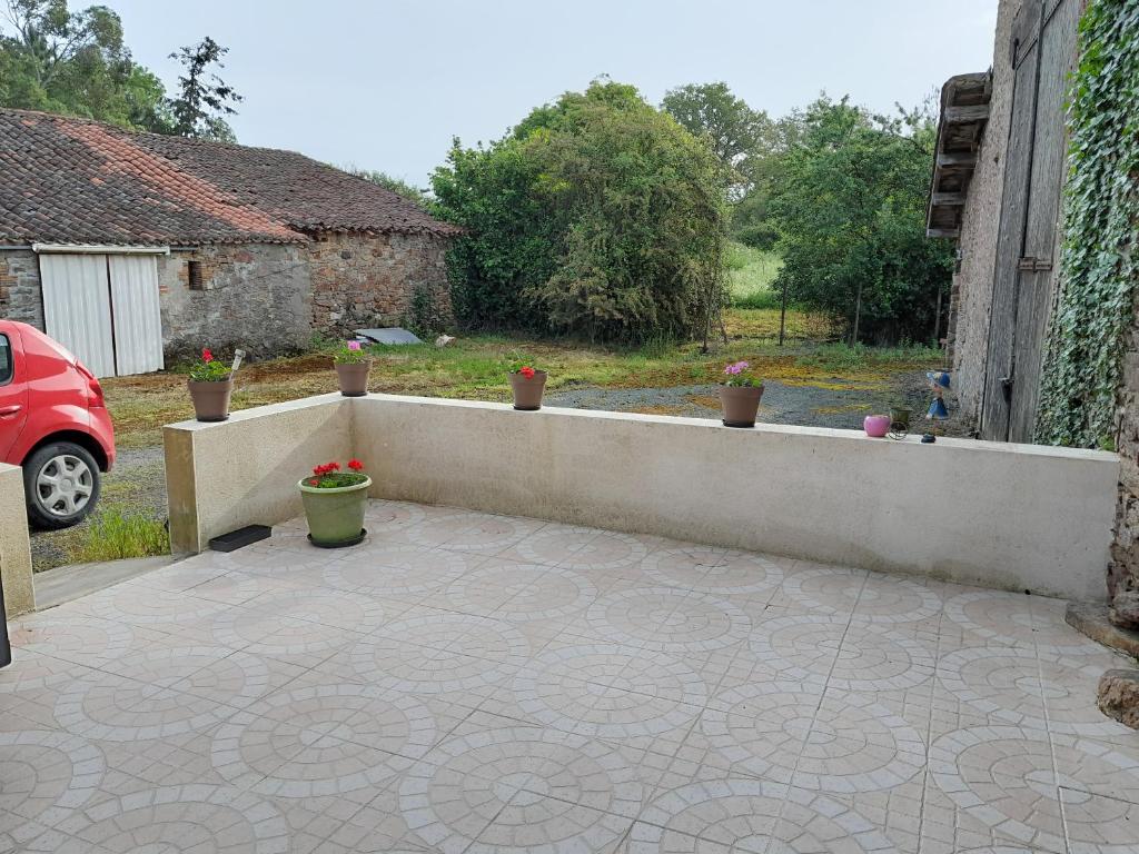 Saint-Hilaire-le-VouhisにあるChambre à la campagneの鉢植えの植物とコンクリートの壁が特徴のパティオ