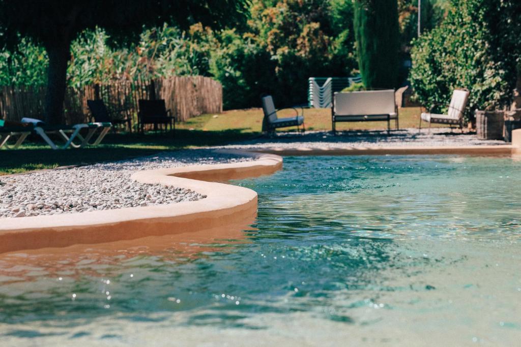a swimming pool in a yard with chairs and tables at Hotel Molí de l'Escala in L'Escala