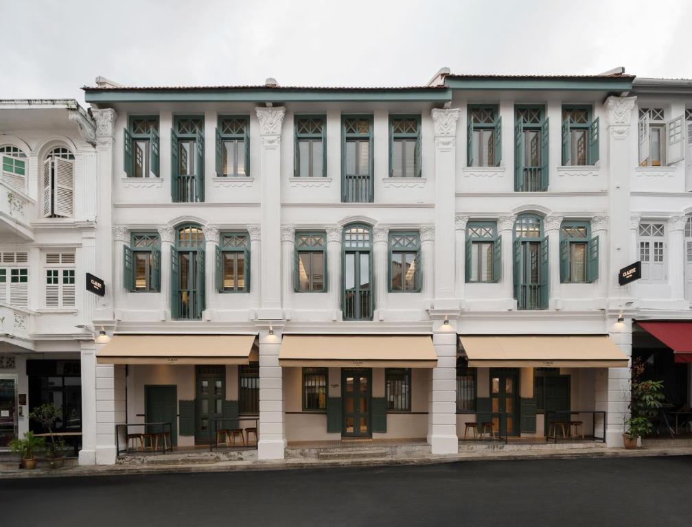 a white building with tables in front of it at Claude Hotel in Singapore