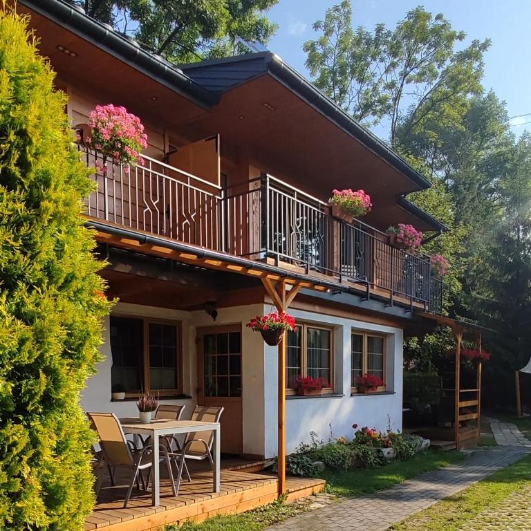 a house with a balcony and a table at Apartamenty Cicha Dolina in Jurgów