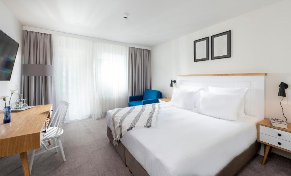 a hotel room with a large bed and a desk at Precise Resort Marina Wolfsbruch - Familienapartments in Rheinsberg