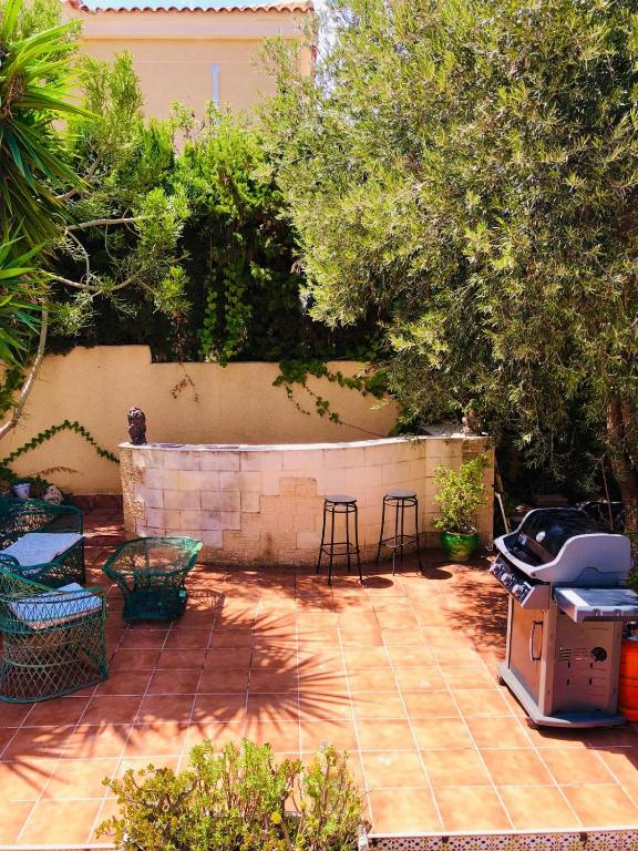 a patio with two chairs and a grill in a backyard at Casa Jardín SevillaMia in Orihuela Costa in Orihuela Costa