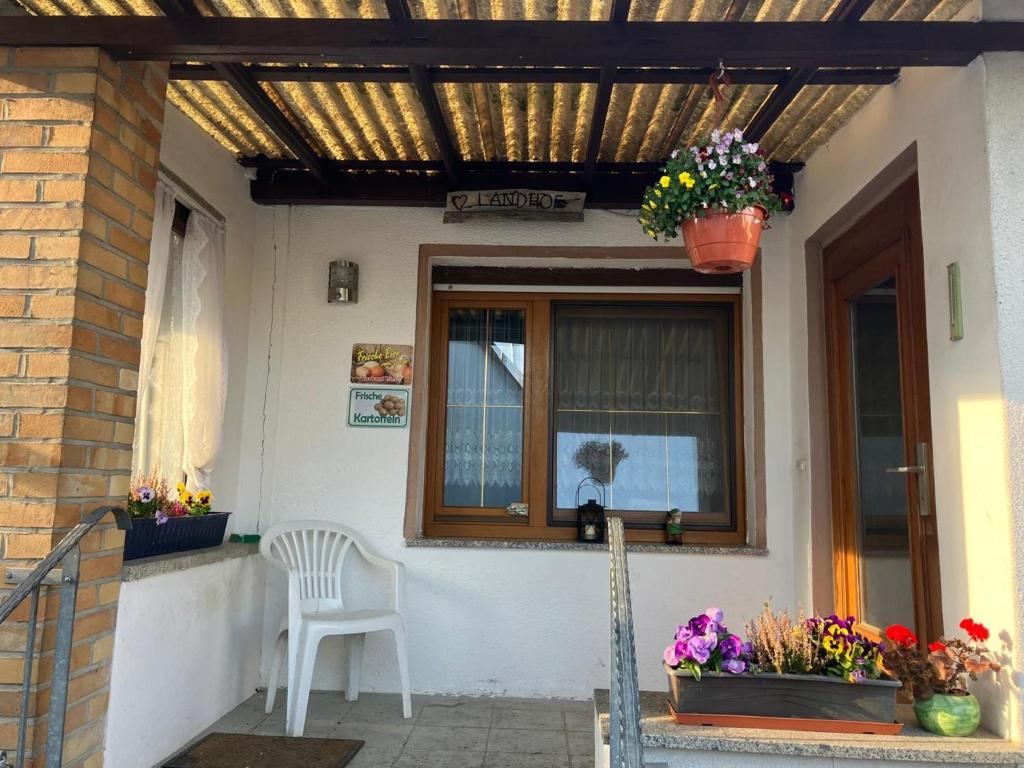 a patio with a window and a chair and flowers at Landhof Lindner in Lüptitz