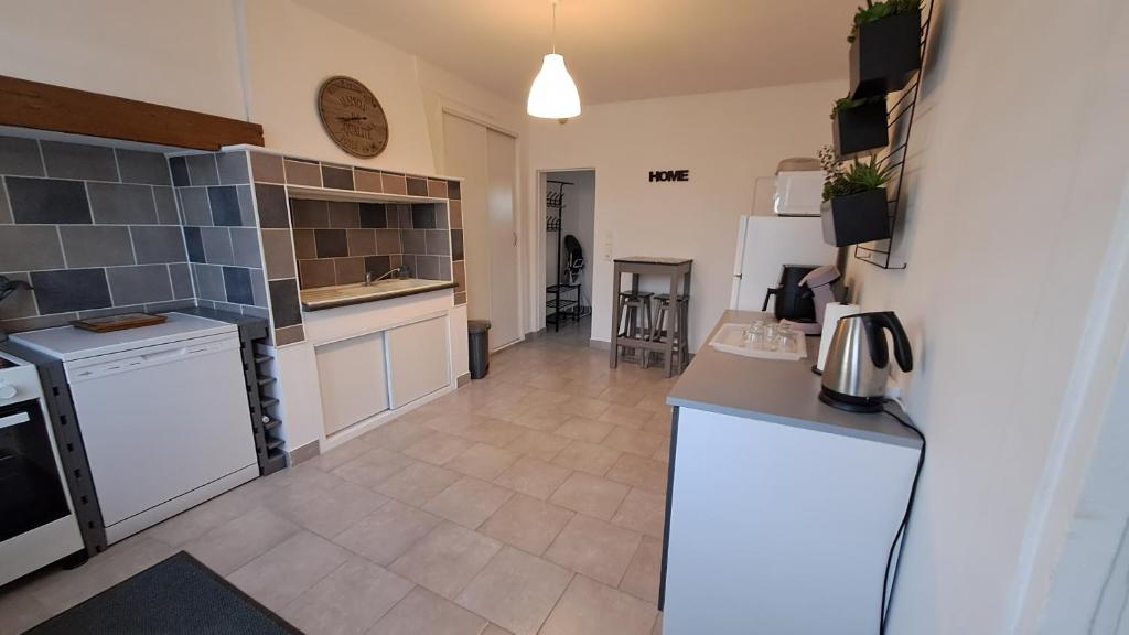 Il comprend une cuisine avec des appareils électroménagers blancs et du carrelage. dans l'établissement Maison à la Campagne, à Duclair