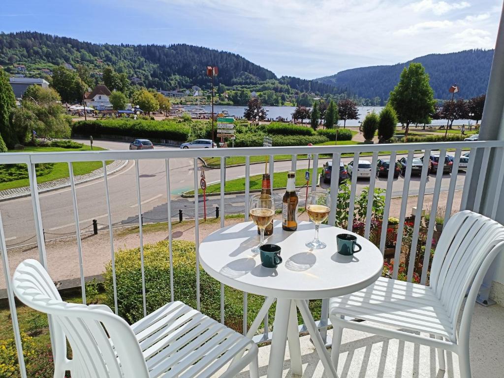 - une table avec deux verres de vin sur le balcon dans l'établissement Au Bord du Lac - Appt 6p vue lac et montagne, à Gérardmer