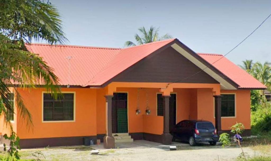 una casa arancione con una macchina parcheggiata di fronte di Malin's Homestay Kota Bharu a Kota Bharu