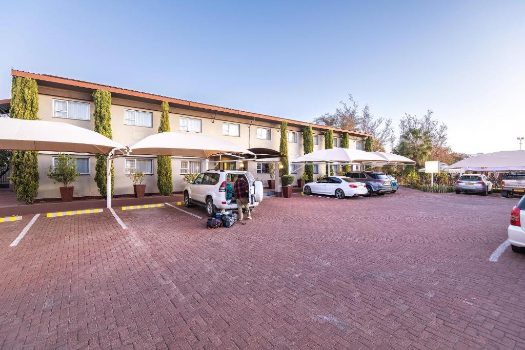 a building with cars parked in a parking lot at Auas City Hotel in Windhoek