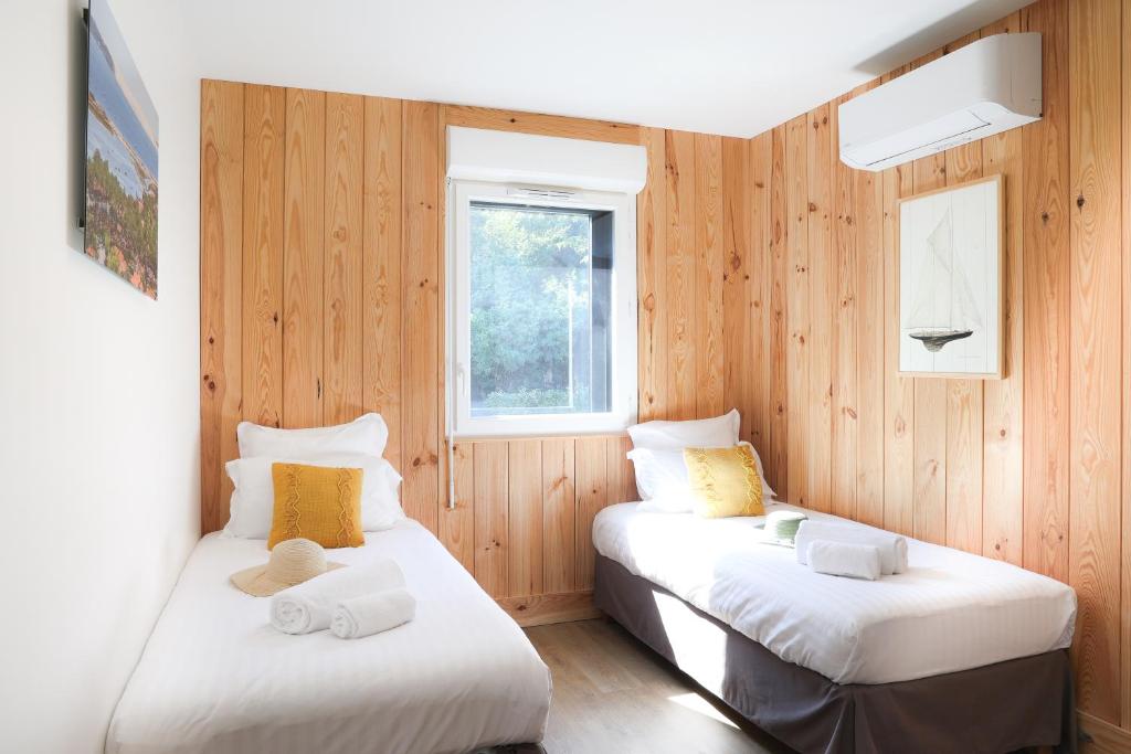 two beds in a room with wooden walls at Résidence Les Suites Du Ferret in Cap-Ferret