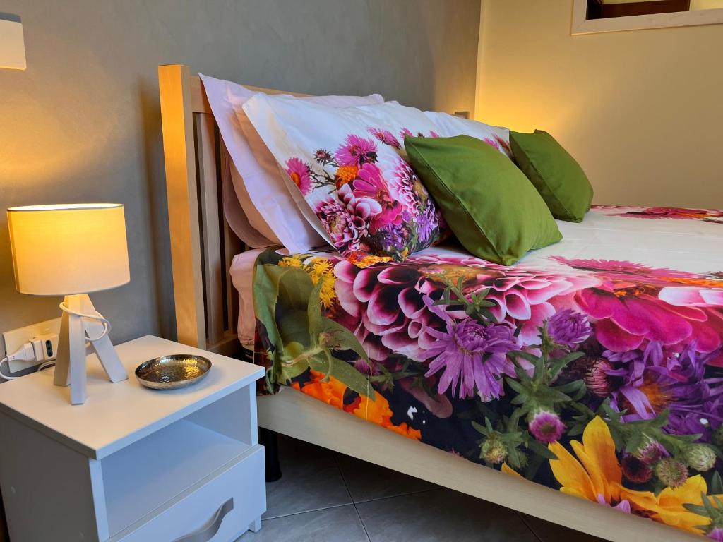 łóżko z kwiatową kołdrą i stołem z lampką w obiekcie L'Acero Home w mieście Baveno