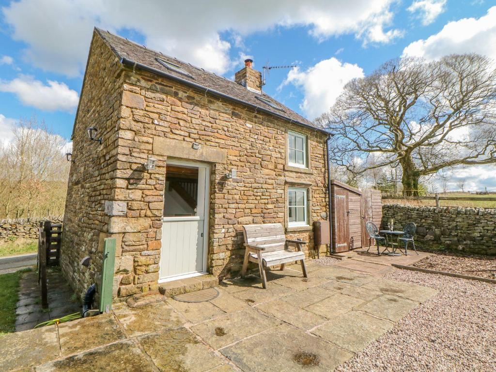 a small stone house with a man on the roof at School House Cottage in Buxton