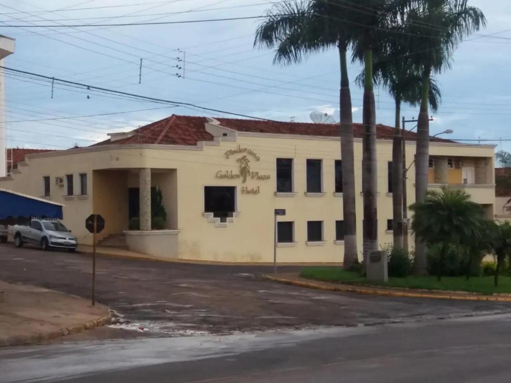 a white house with palm trees in front of it at Pindorama Golden Plaza Hotel - Pindorama SP in Catanduva
