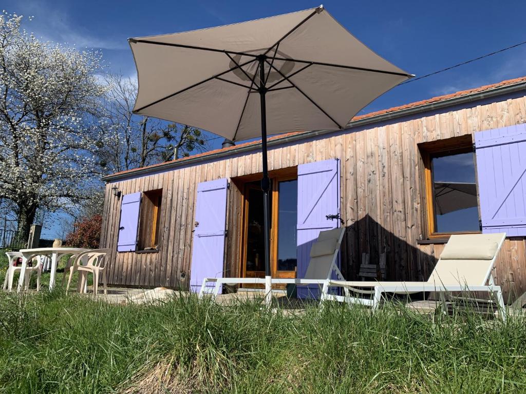 une maison avec des chaises et un parasol devant elle dans l'établissement Maison insolite de mi-montagne, à Pébrac