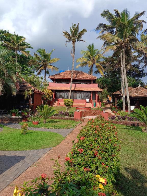 a house with palm trees in front of a garden at Blue Water Beach Resort in Varkala